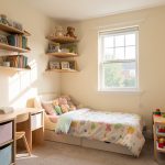 Petite chambre d’enfant lumineuse avec un mobilier compact, des rangements muraux et une ambiance douce, ordonnée et chaleureuse.