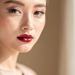 Portrait rapproché d’une jeune femme au teint frais et lumineux, avec des lèvres rouge cerise satinées, photographiée en lumière naturelle dans un style éditorial haut de gamme.